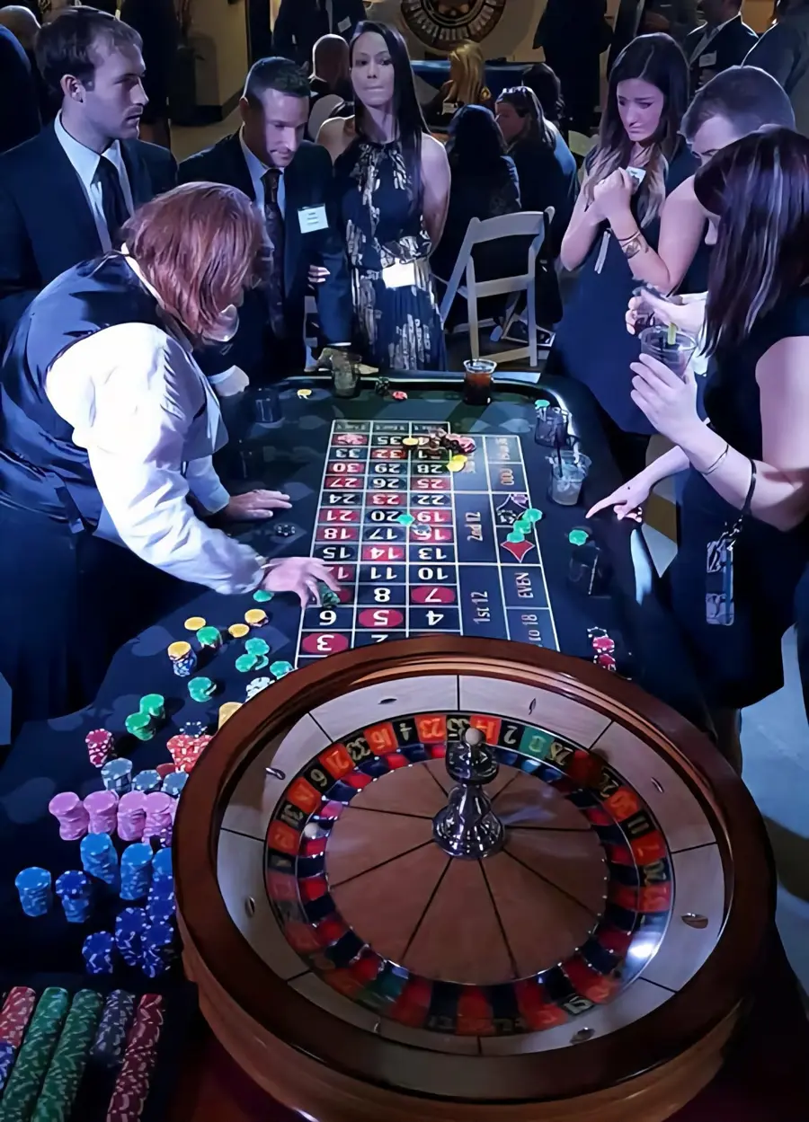 A dealer works beside guests at a roulette table during a casino-party event.